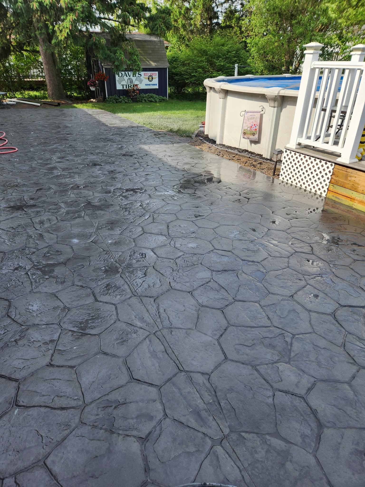 Stamped cobblestone patio near pool by S&T Concrete